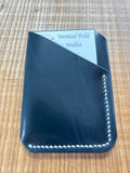 Black leather wallet with 'Vertical Fold Wallet' label on a wooden surface