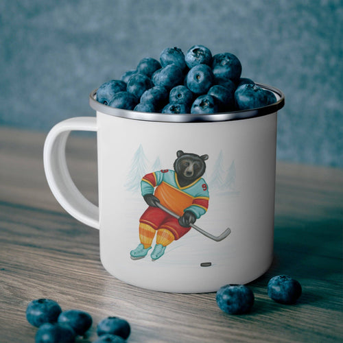 Mug with a bear hockey player design filled with blueberries on a wooden surface.