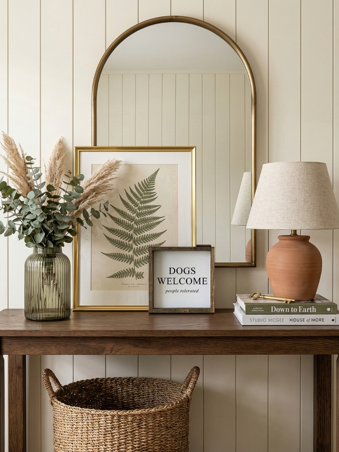 Nestled corner with a wooden table, framed picture, lamp, books, and decorative items against a light wood paneled wall.