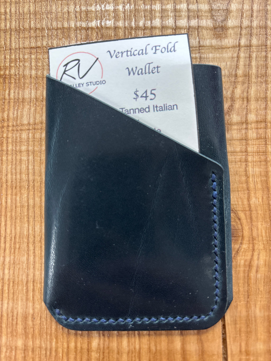 Black leather wallet with a visible brand label on a wooden surface