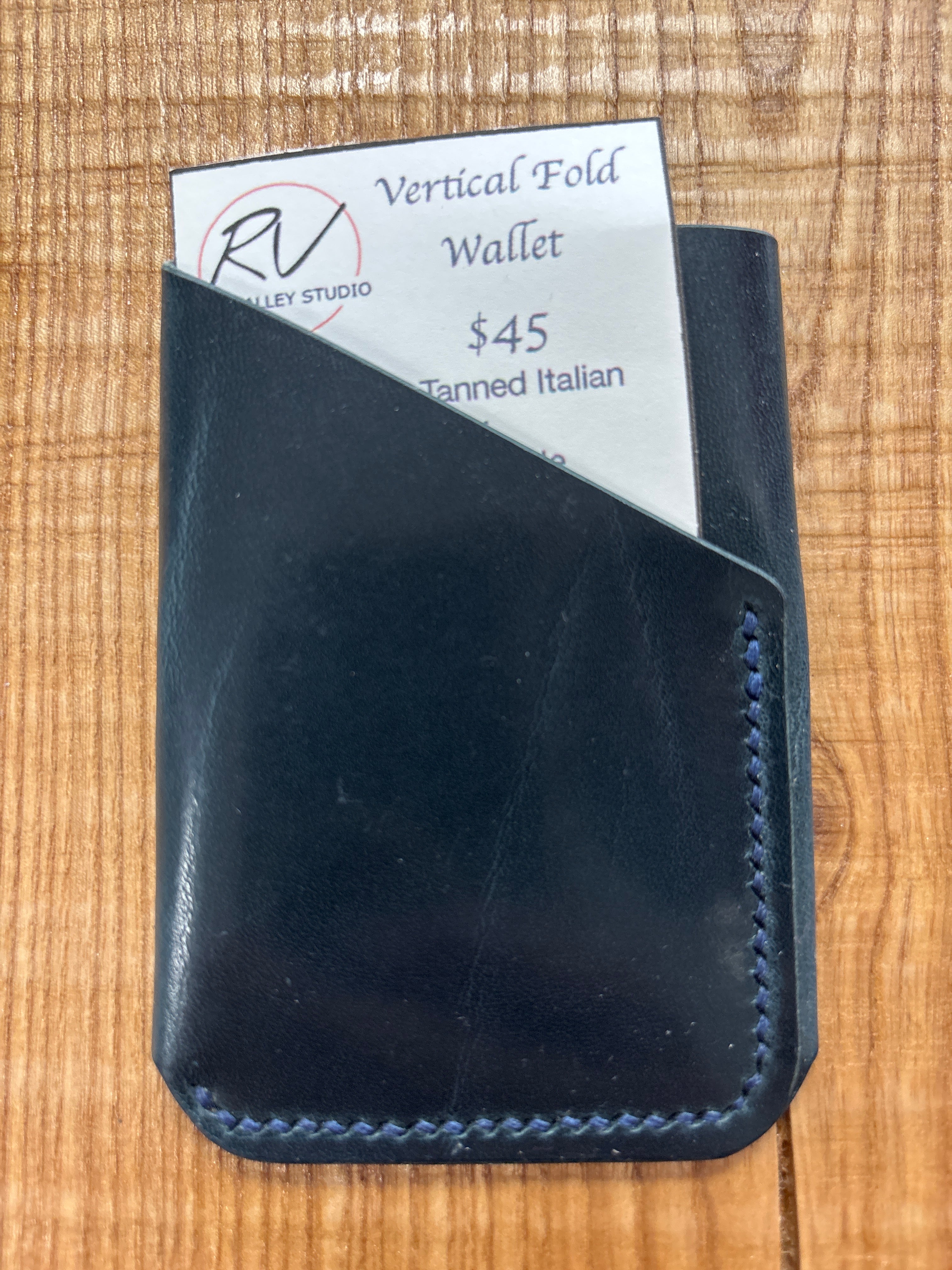 Black leather wallet with a visible brand label on a wooden surface
