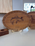 Wooden cribbage board with fish design on a stand indoors.