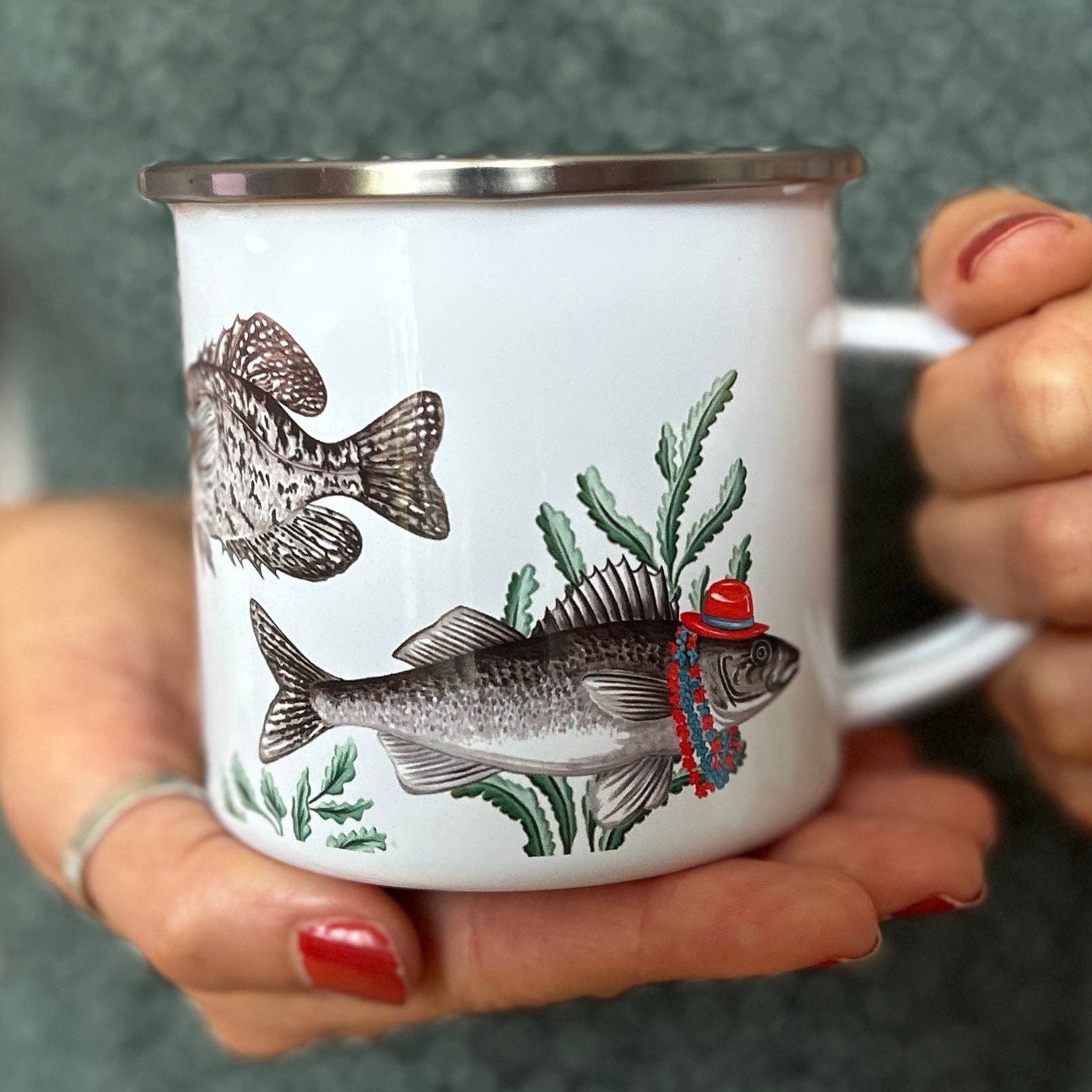 Person holding a mug with fish illustrations in a casual setting