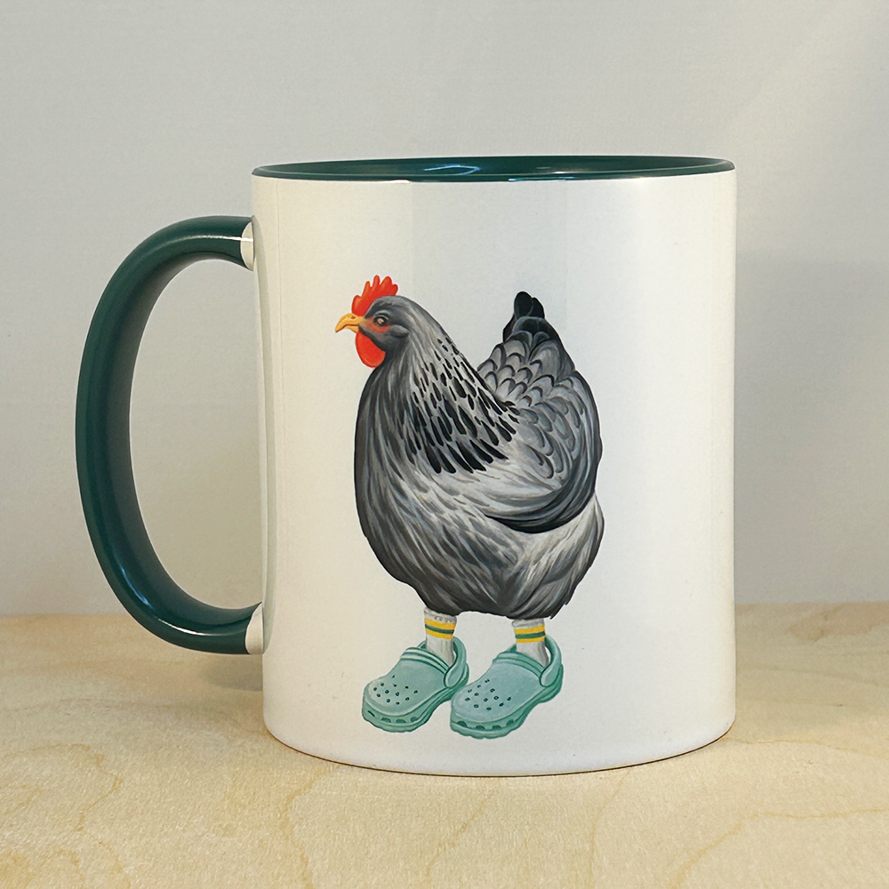 Mug with a chicken wearing crocs design on a wooden surface.