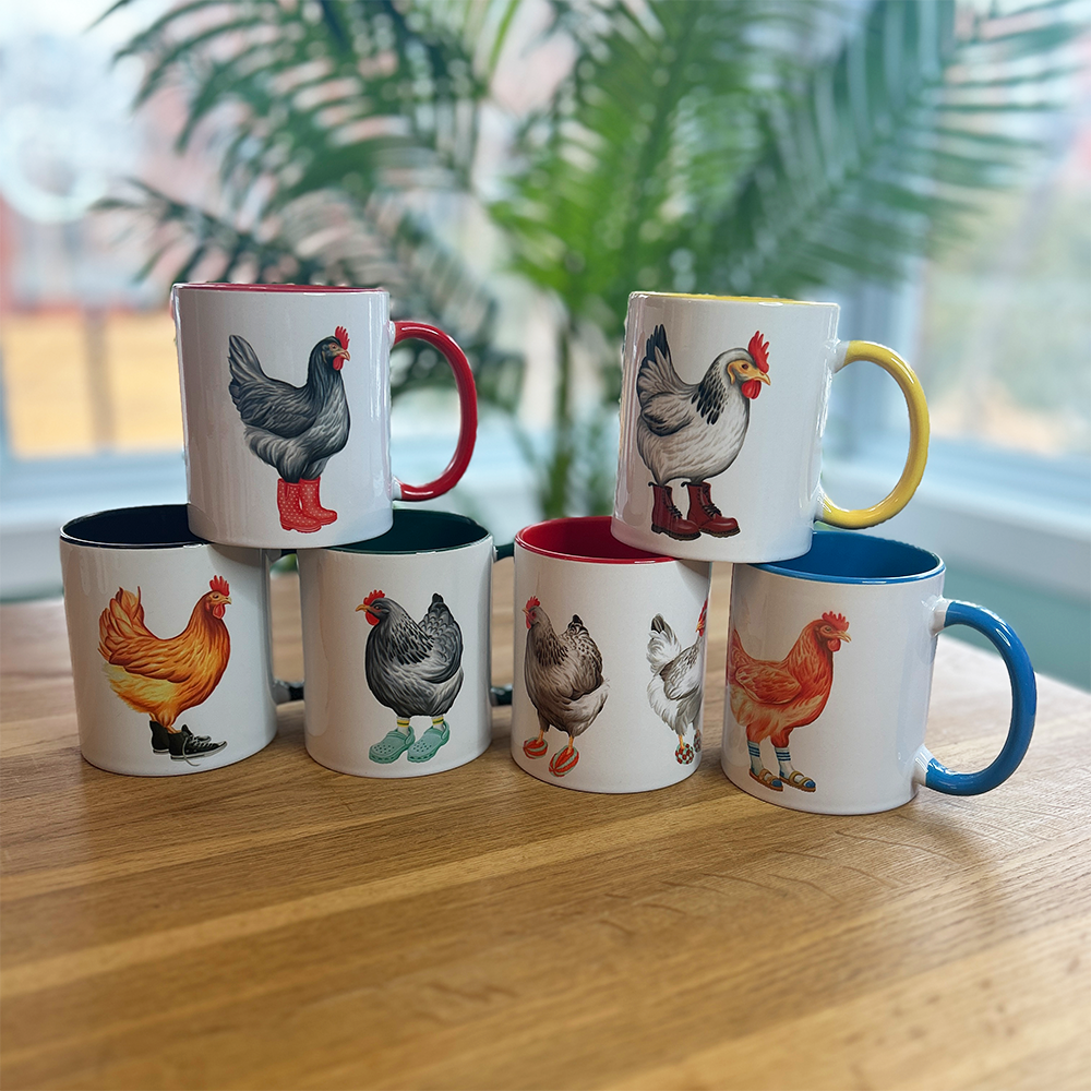 Set of six mugs with chicken illustrations on a wooden surface.