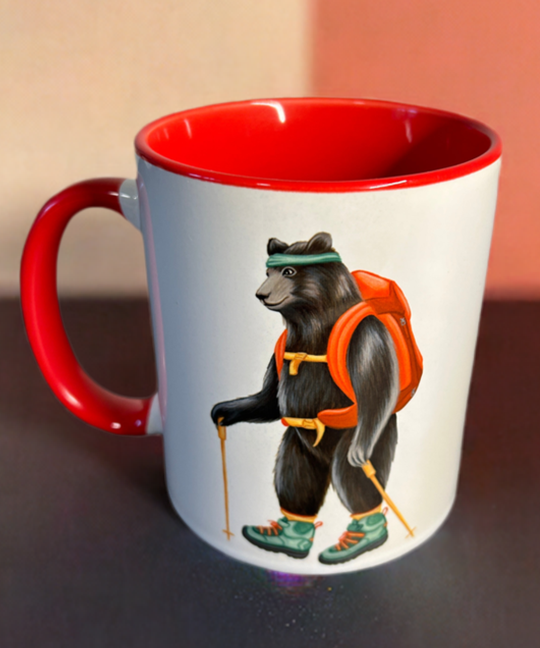 Mug with a bear design wearing a backpack on a dark surface with a colorful background