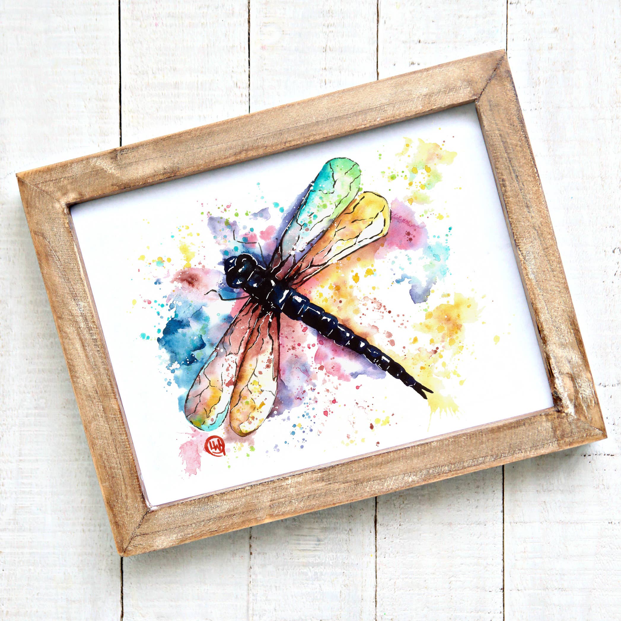 Framed watercolor painting of a dragonfly on a white background