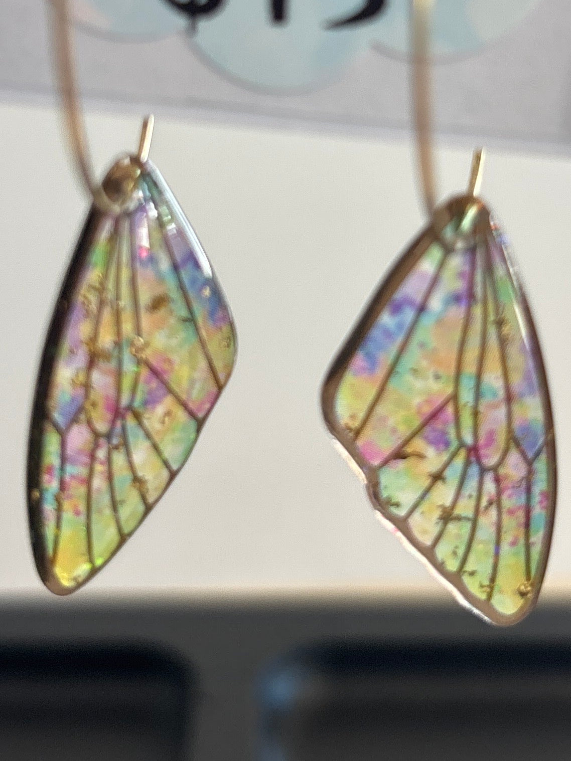 Colorful butterfly-shaped earrings on a Hollywood North Jewelry label with price tag.