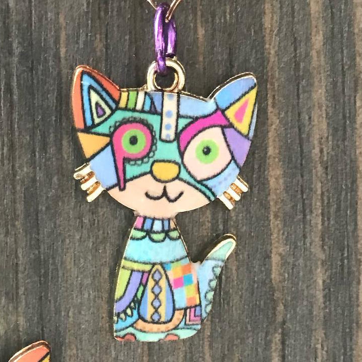 Colorful cat-shaped pendants on chains against a wooden background