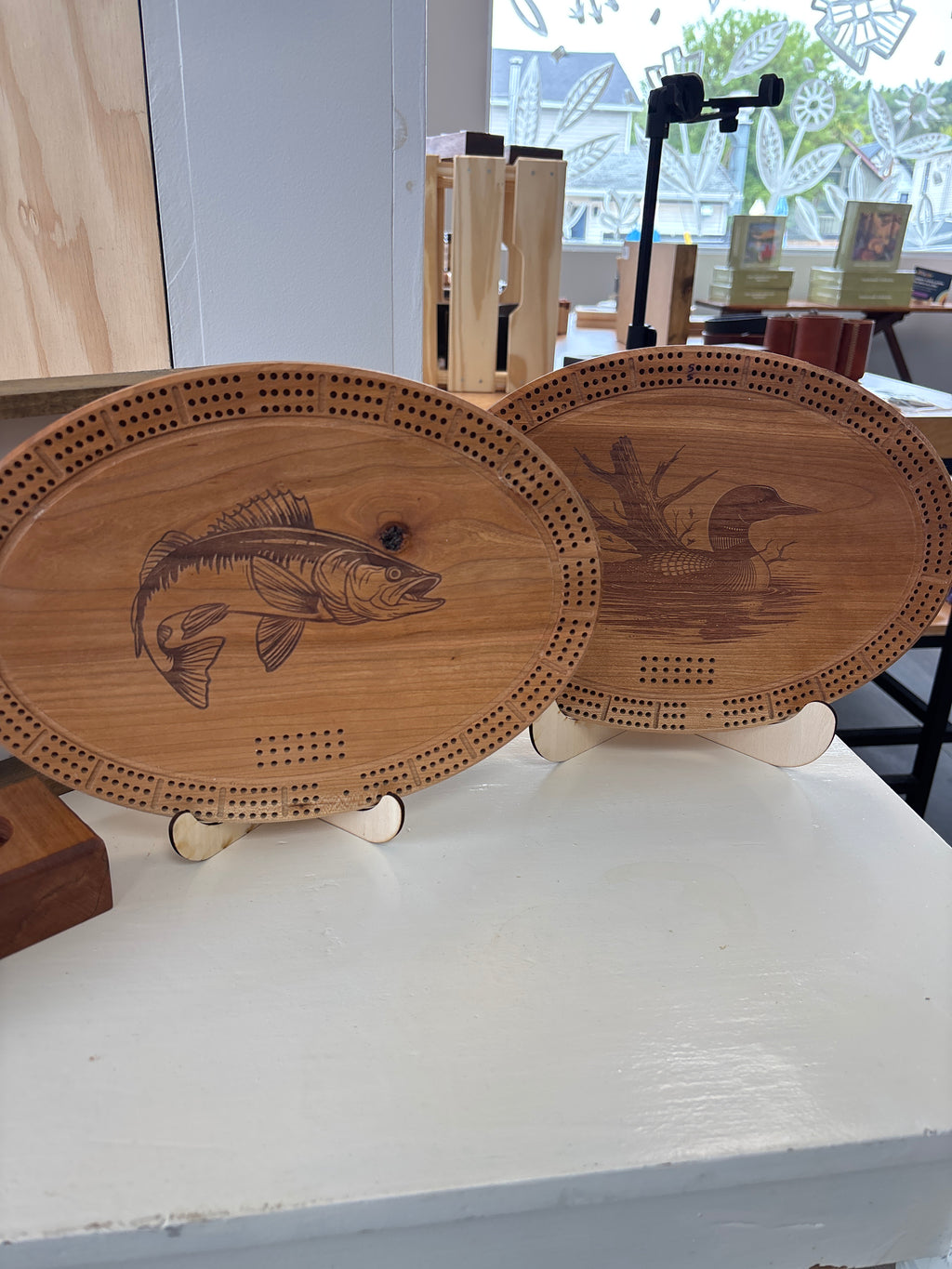 Wooden cribbage boards with fish designs on a white surface.