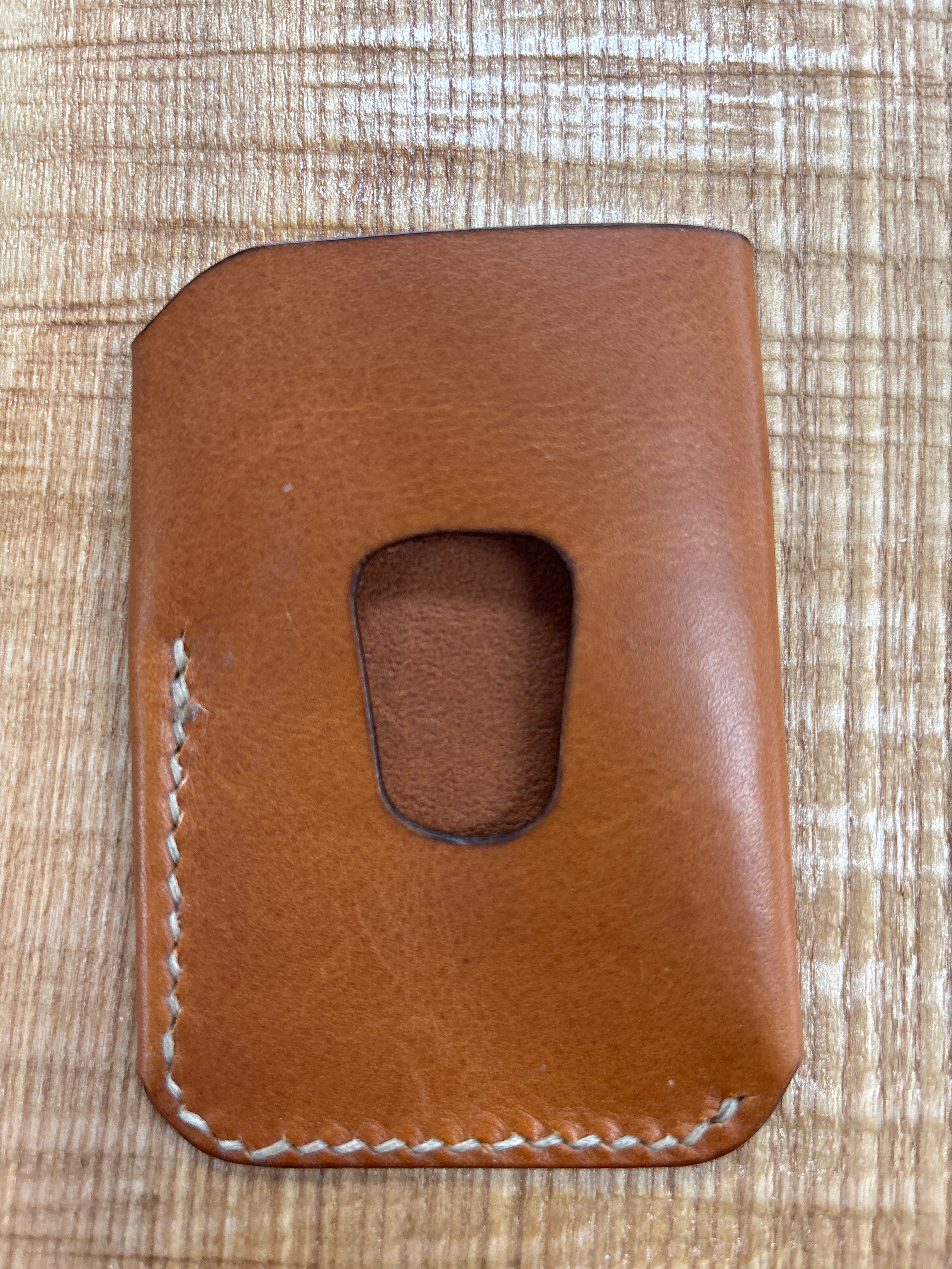 Brown leather cardholder on a textured beige surface