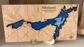 Wooden map of Westport with blue water on a shelf next to books
