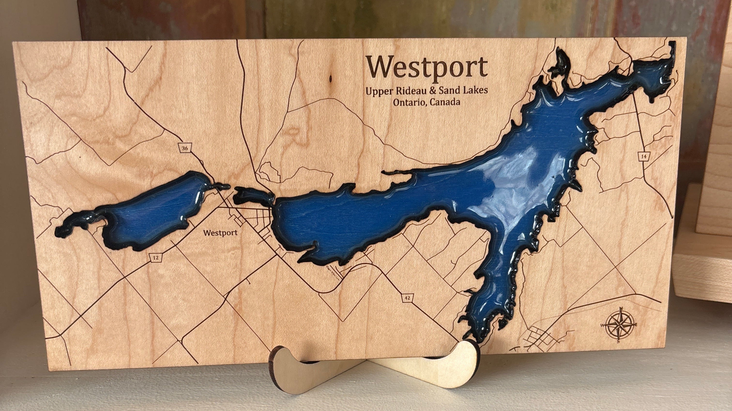 Wooden map of Westport with blue water on a shelf next to books