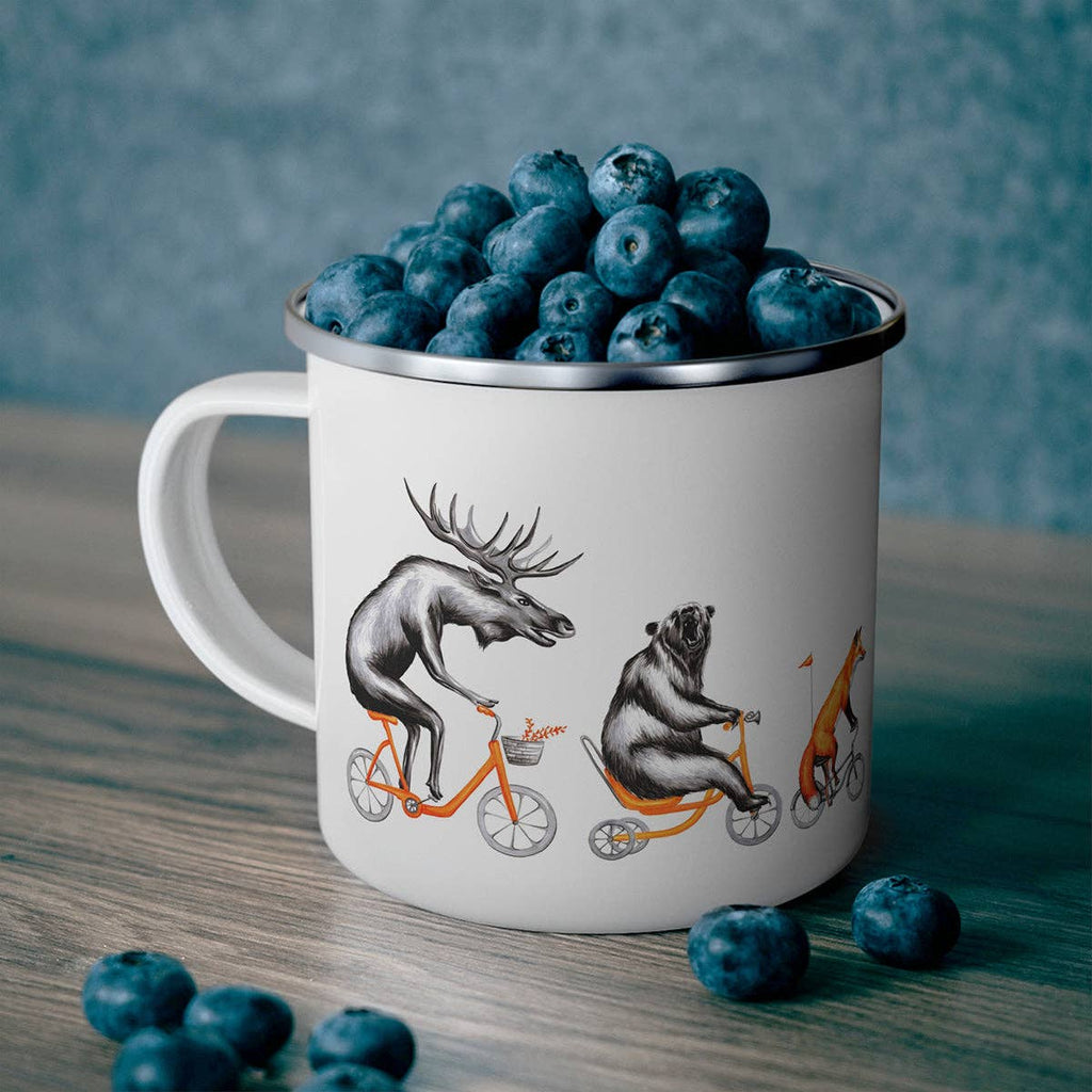 Mug with animal illustrations filled with blueberries on a wooden surface.