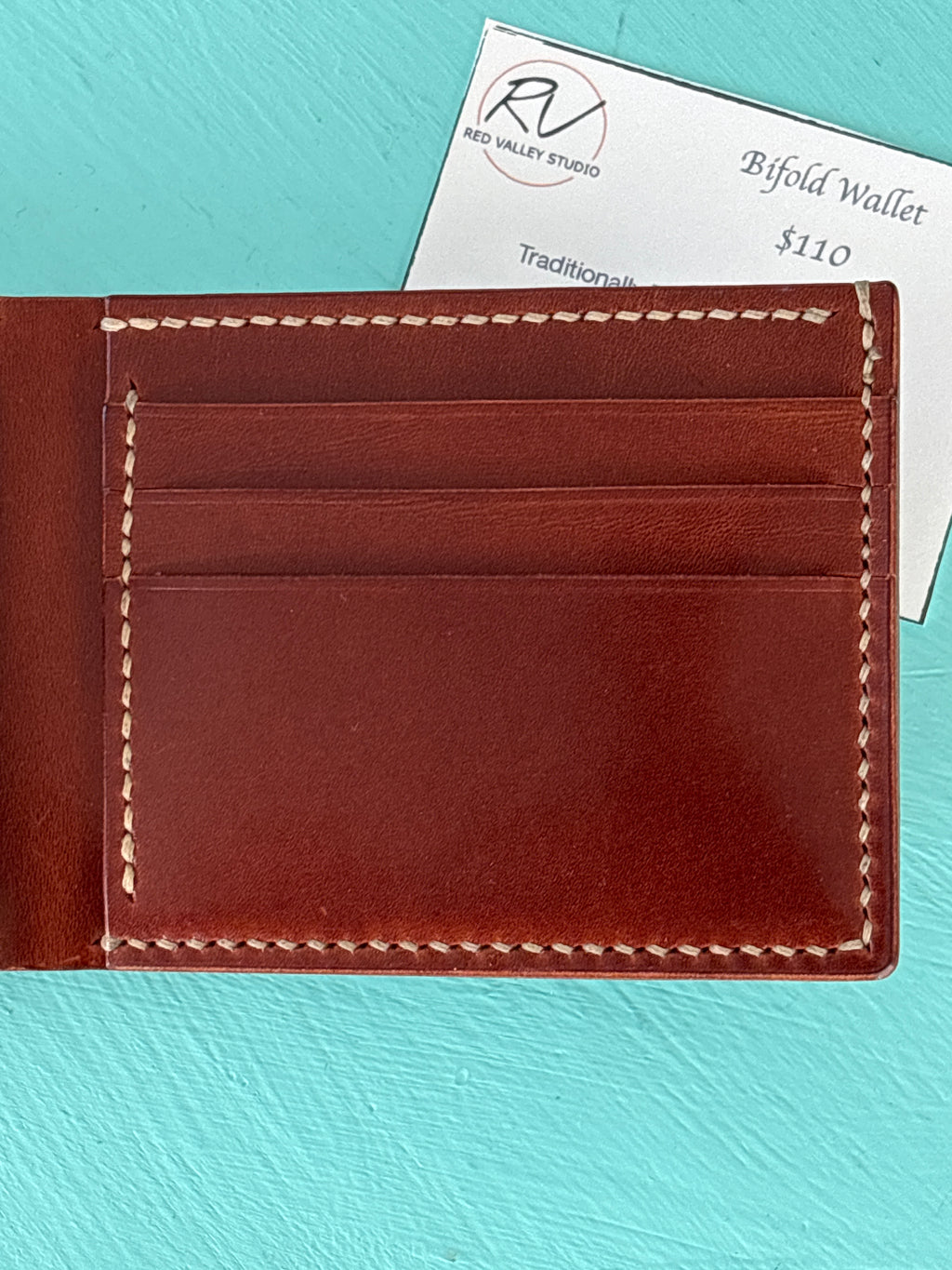 Brown leather wallet with visible stitching on a turquoise background