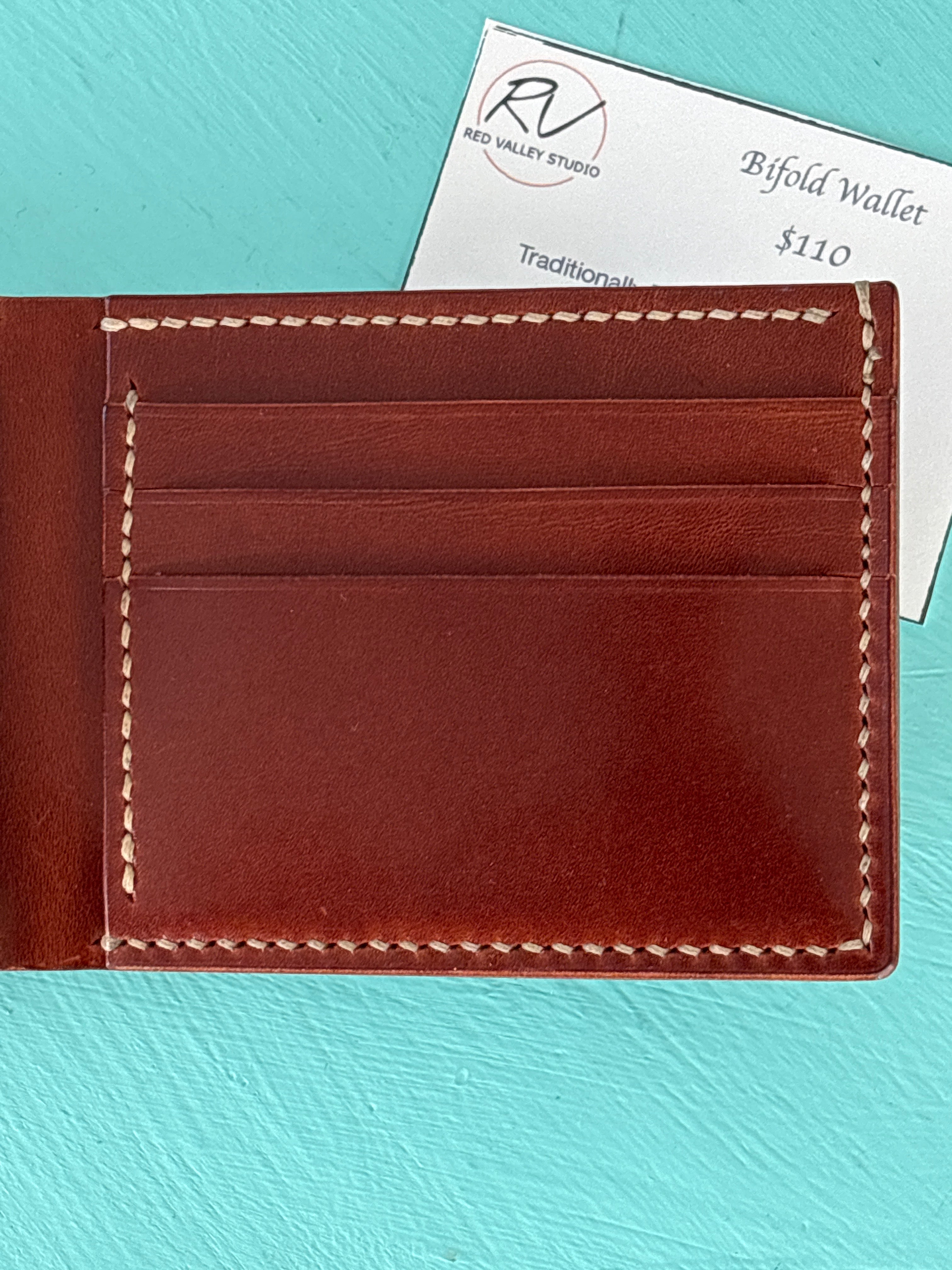 Brown leather wallet with visible stitching on a turquoise background
