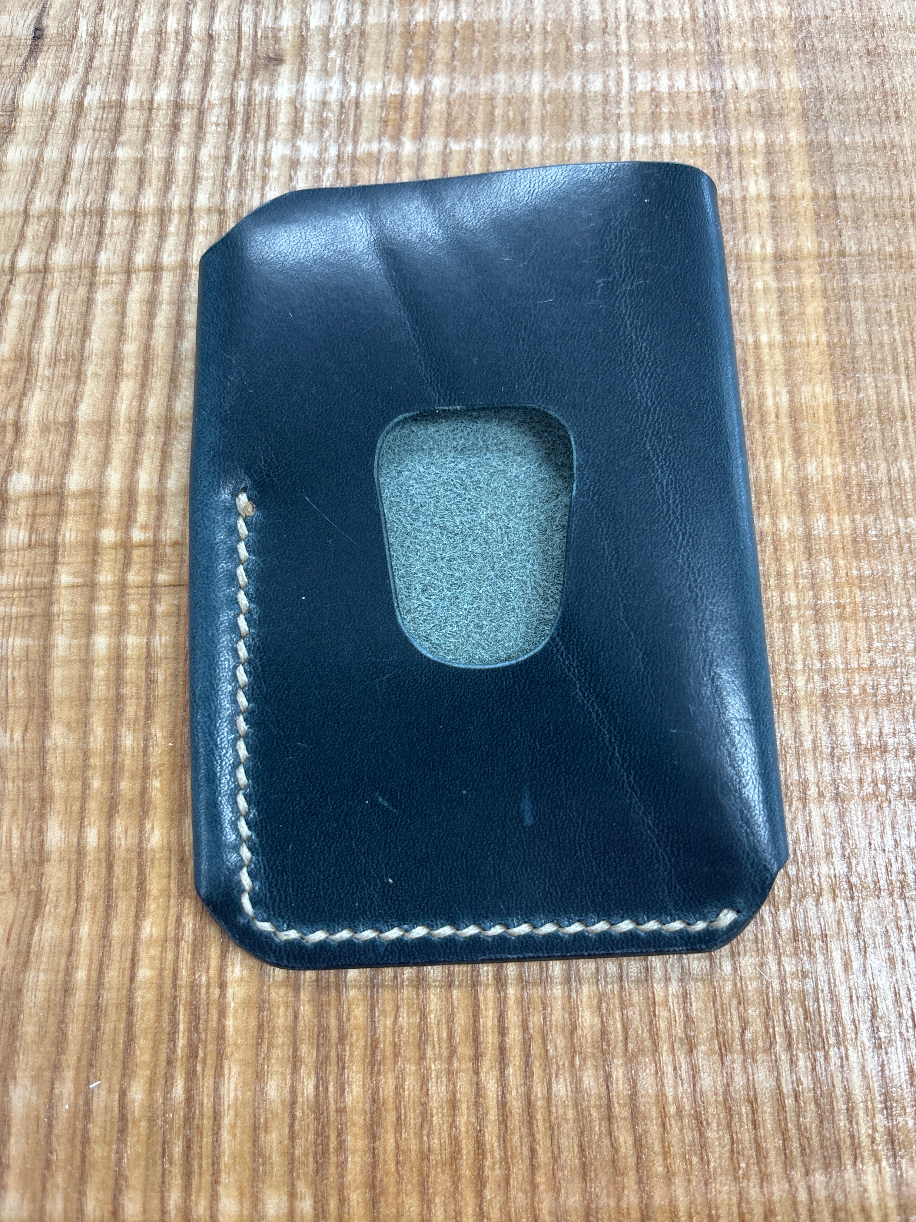Black leather cardholder with a small window on a wooden surface