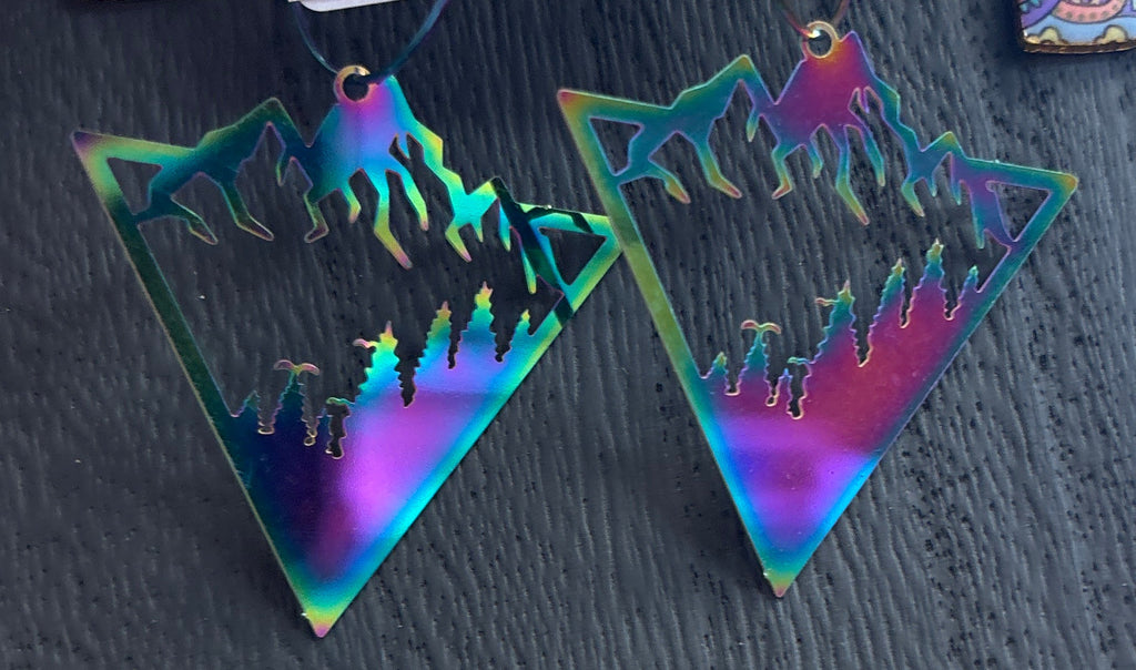 Holographic triangle-shaped earrings on a black surface with a price tag.
