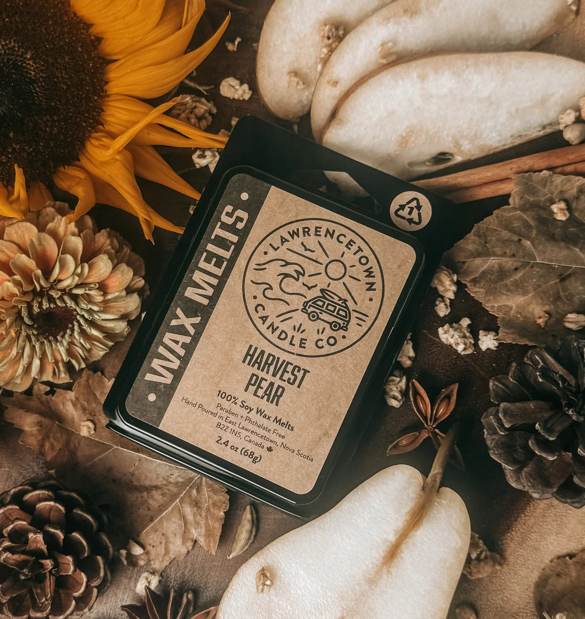A styled flat-lay of a wax melt package labeled 'Wrenchock Farm Co. Harvest Pear' surrounded by autumn props including a sunflower, pears, pinecones, cinnamon sticks, star anise, and dried leaves on burlap.