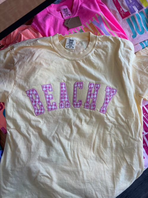 BUTTER t-shirt with 'BEACHY' text in pink on a colorful background