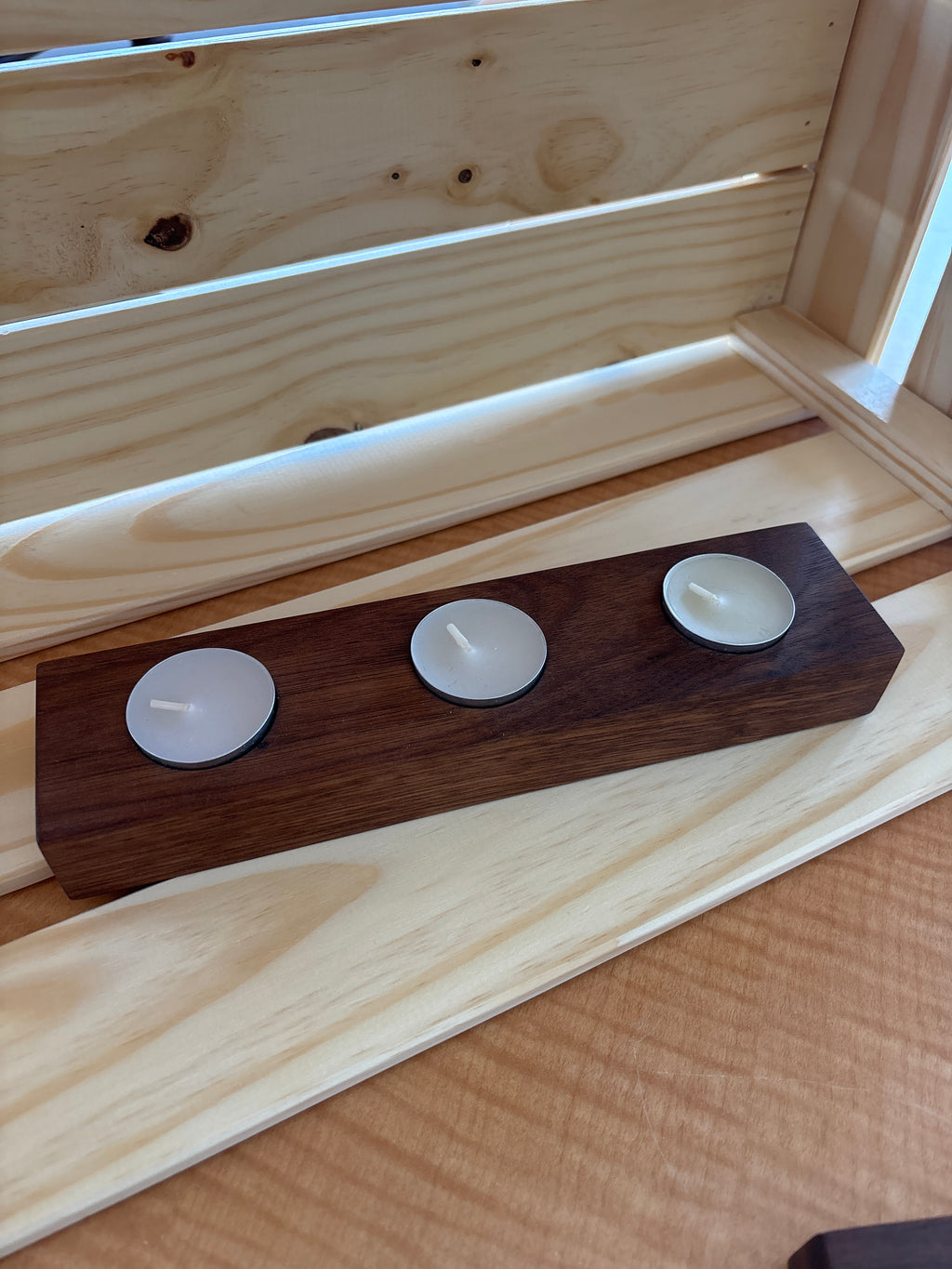 Wooden candle holder with three white candles on a wooden surface