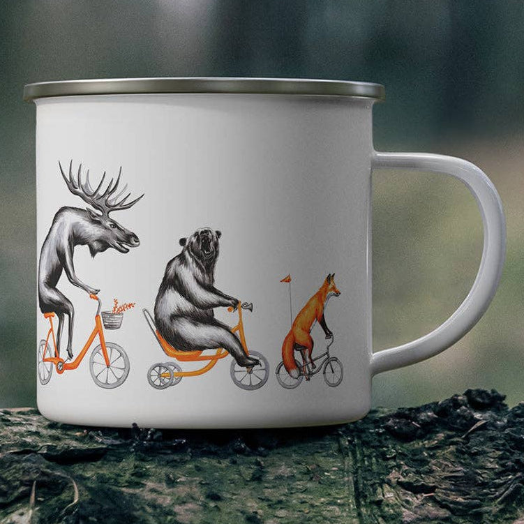 White mug with animal illustrations on a tree stump in a forest setting