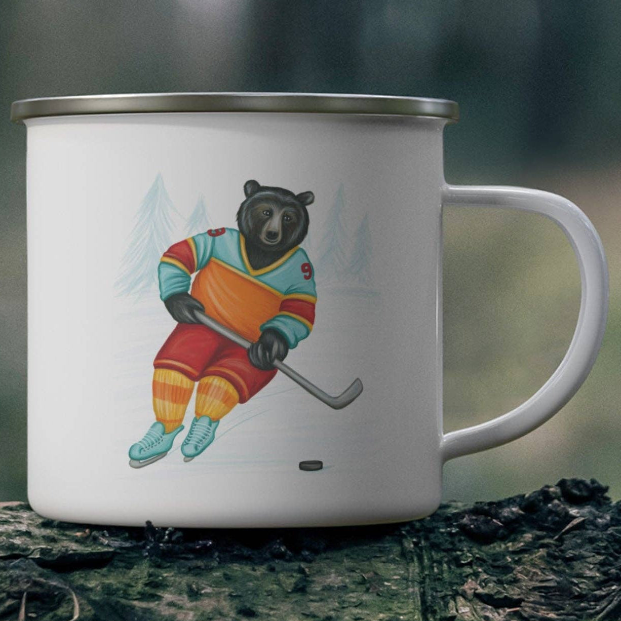 White mug with a bear playing hockey design on a wooden log in a forest setting