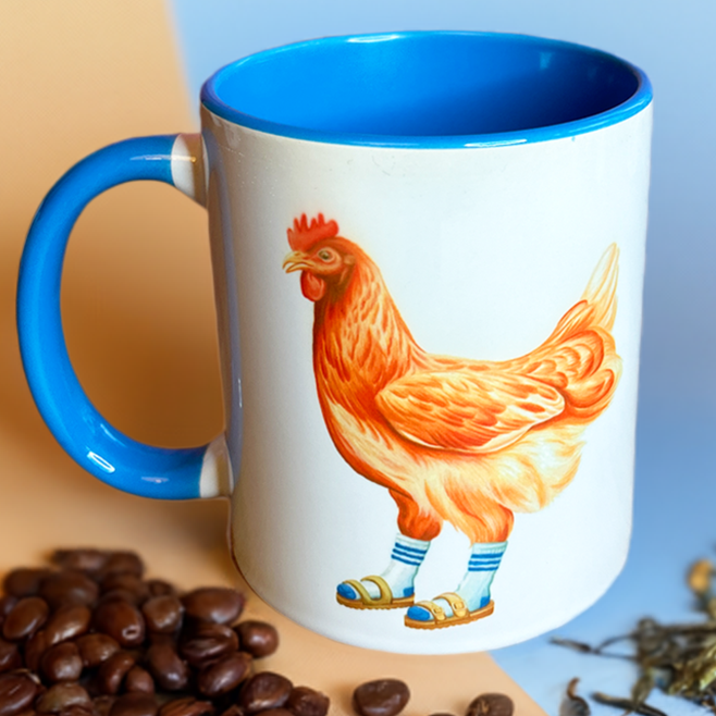 Mug with a rooster design on a beige and blue background with coffee beans and tea leaves.