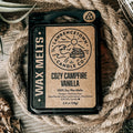 A package of Laurencetown Candle Co. Cozy Campfire Vanilla wax melts, presented in a rustic flat-lay setting with a coiled jute rope, burlap, and dried grass on a wooden surface.