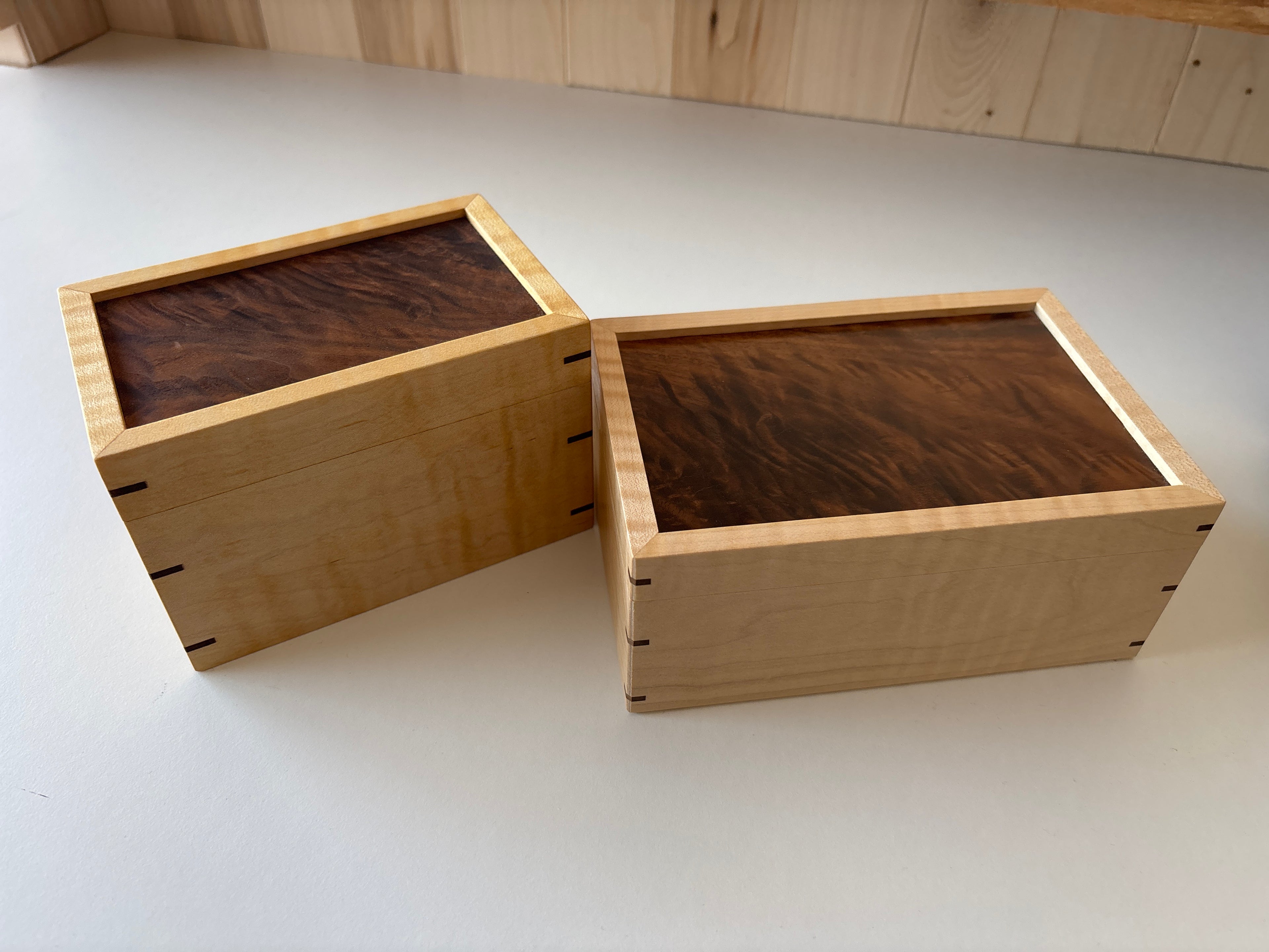 Two wooden boxes with dark brown interiors on a light gray surface.